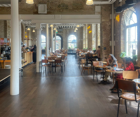 The inside of the Visitors' Book Cafe at Woolwich Works, with people sat at tables.