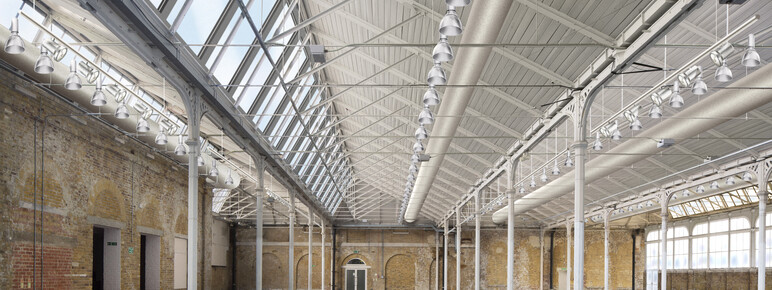 A render of the Fireworks Factory, a large space with a concrete floor, brick walls, and a metal and glass roof.