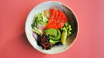 A pokay bowl of salmon and lots of green veg, on a pale pink background.