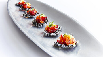A long plate of beetroot and salmon canapes on a white background